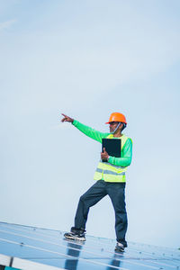 Low angle view of man with umbrella standing against sky