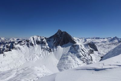 Scenic view of snowcapped mountains against clear blue sky