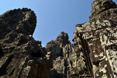 Low angle view of rocks against clear blue sky