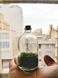 Close-up of hand holding bottle against built structure