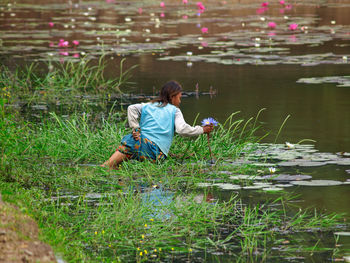 Rear view of man sitting by lake