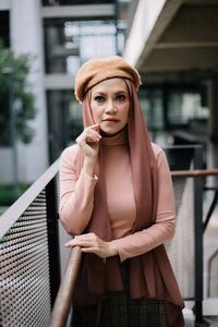 Portrait of woman standing by railing