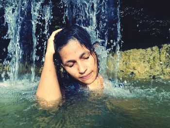 Close-up of woman under waterfall