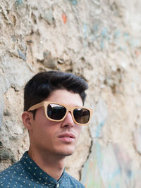 Portrait of smiling man wearing sunglasses against wall