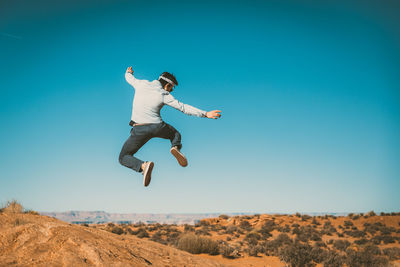 Low angle view of man jumping against clear sky