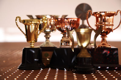Close-up of trophies on table against wall