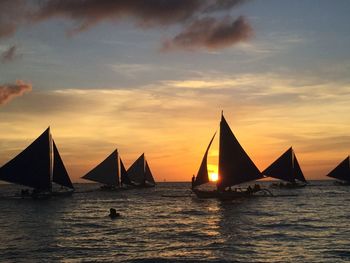 Sailboats sailing in sea against sky during sunset