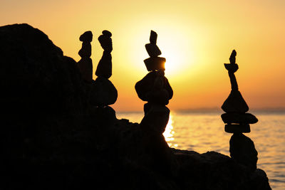 Silhouette stack of rock at beach against sky during sunset