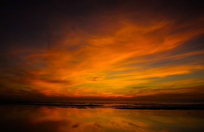 Scenic view of sea against dramatic sky during sunset