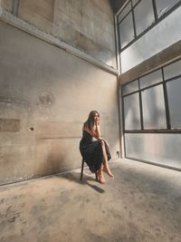 Side view of young woman standing against wall