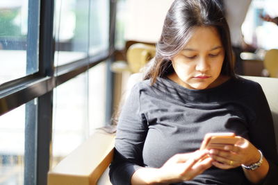 Woman using mobile phone while sitting at cafe