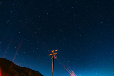 Low angle view of electricity pylon against sky at night