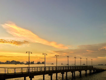 Silhouette pier over sea against sky during sunset