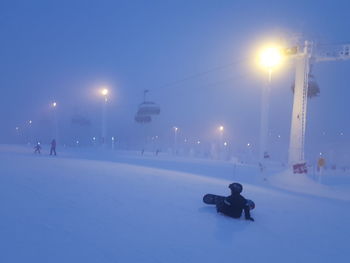 Child skateboarding on snow covered field against sky