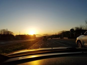 Cars on street seen through windshield during sunset
