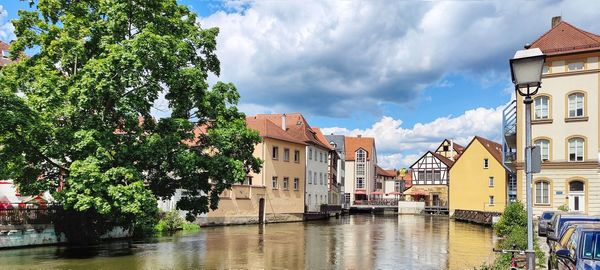 Buildings by river against sky