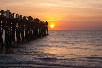 Pier over sea against sky during sunset