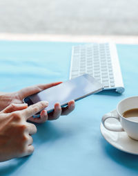 Midsection of person holding coffee cup by swimming pool