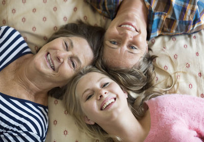 Overhead portrait of happy three generation females lying on bed