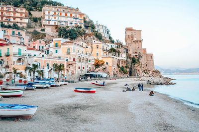 People on beach by buildings against sky in city