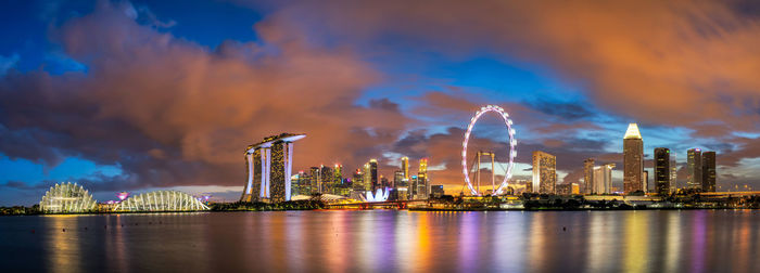 Illuminated city against cloudy sky