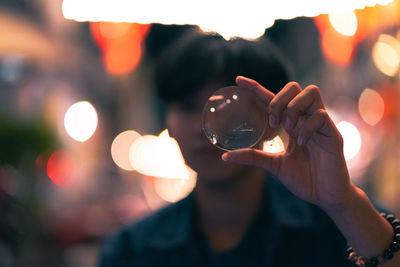 Midsection of person holding illuminated crystal ball