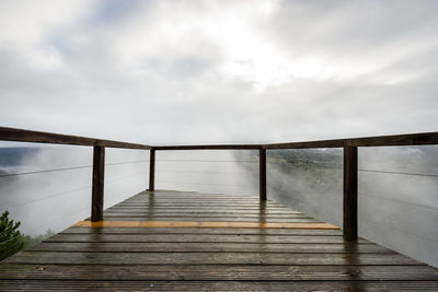 Footbridge over footpath against sky