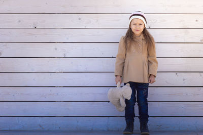 Portrait of young woman standing against wall