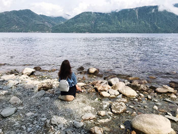 Rear view of woman sitting on rock