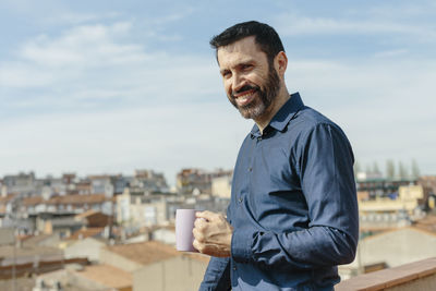 Portrait of man standing by cityscape against sky