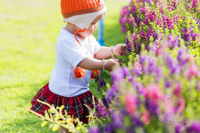 The image of a cute little girl happily picking flowers in the garden.