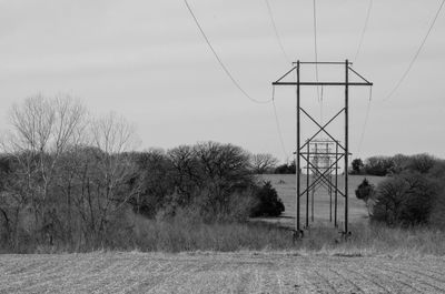 Electricity pylons on field against sky