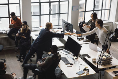 Businessman giving box to female colleague while working in office