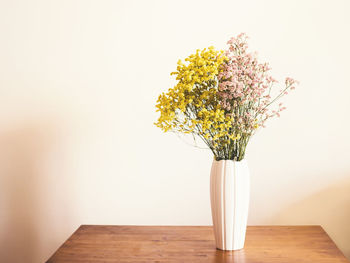 Close-up of flower vase on table against wall