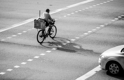 Rear view of man riding bicycle with crate on street