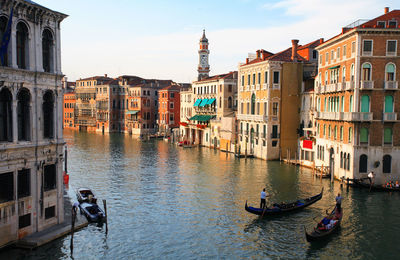 Gondolas on grand canal amidst buildings against sky