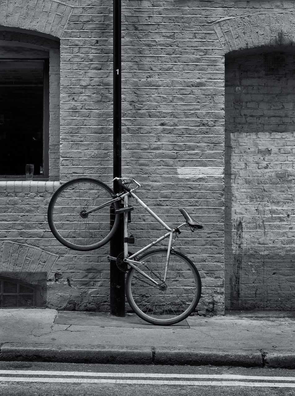 BICYCLE PARKED AGAINST BRICK WALL