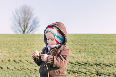 Cute girl holding stick while standing on land