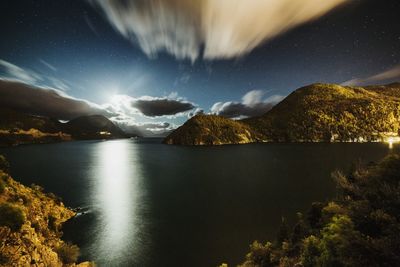 Scenic view of lake and mountains against sky at night