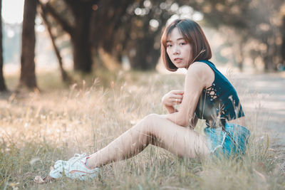 Side view of woman sitting on field