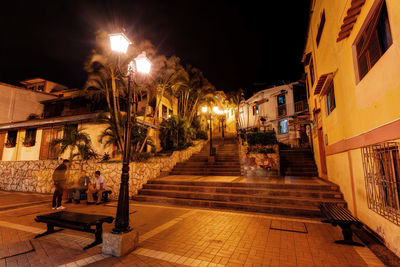 Illuminated street amidst buildings in city at night