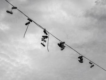 Low angle view of cranes hanging on rope against sky