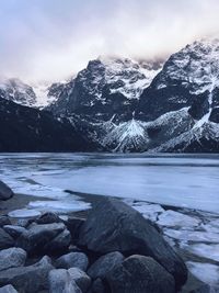 Scenic view of frozen lake by snowcapped mountains against sky