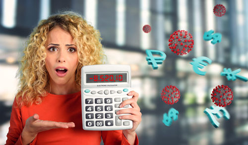 Digital composite image of woman holding calculator by currency symbol and virus