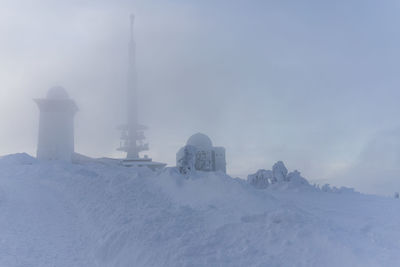 Snow covered buildings against sky