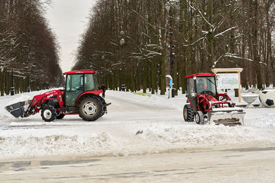 Tractor on road by trees during winter