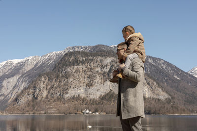 Father and son enjoying mountains, snow, lake, good weather, blue sky, sun. 