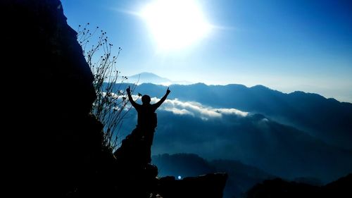 Silhouette person standing on mountain against sky