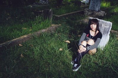 Full length of young woman sitting on grassy field