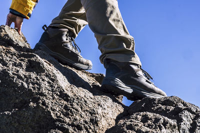 Low section of man on rock against sky